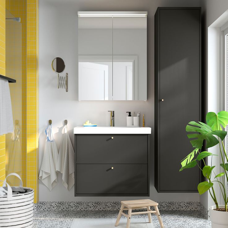 a bathroom with grey cabinets and yellow accents