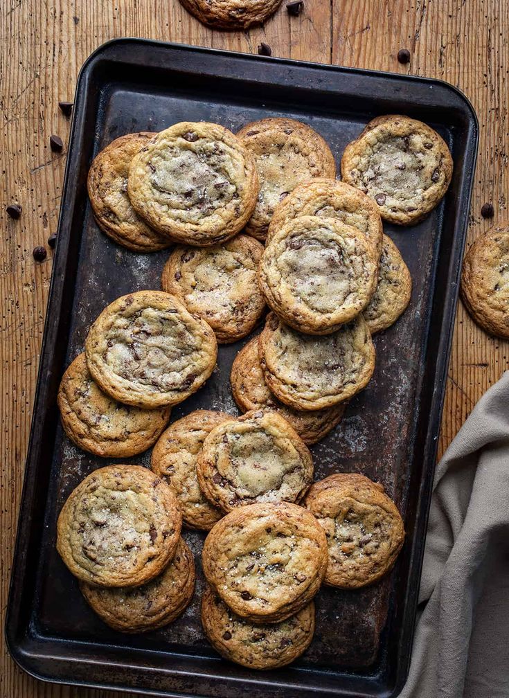 chocolate chip cookies on a baking sheet with one cookie in the middle and more scattered around