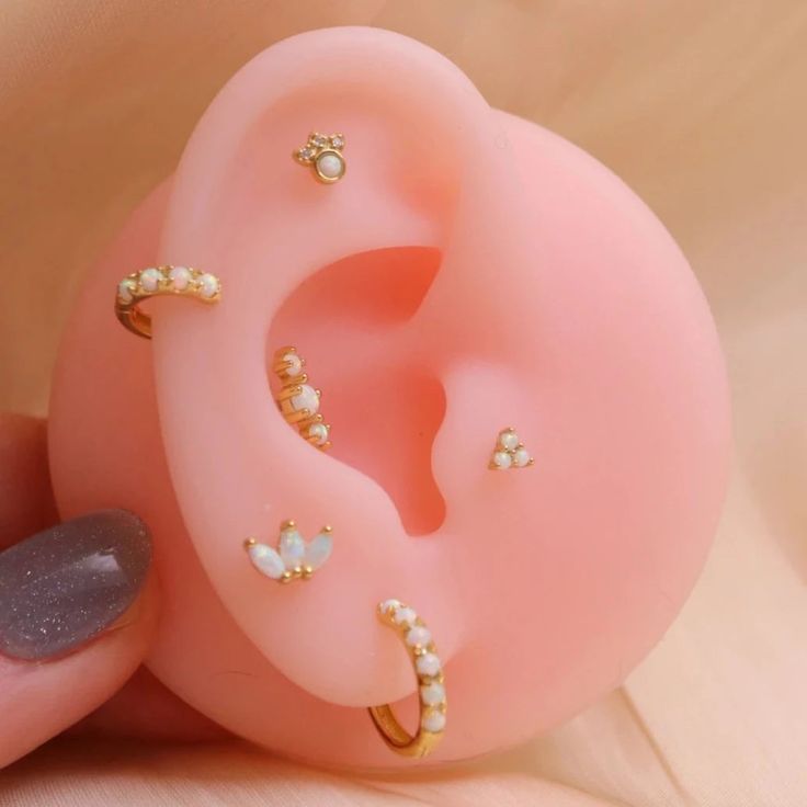 a person holding a fake pink ear with gold and white beads