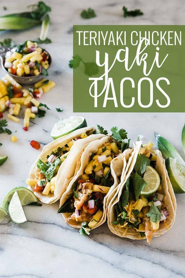 three tacos on a marble counter with limes and cilantro in the background