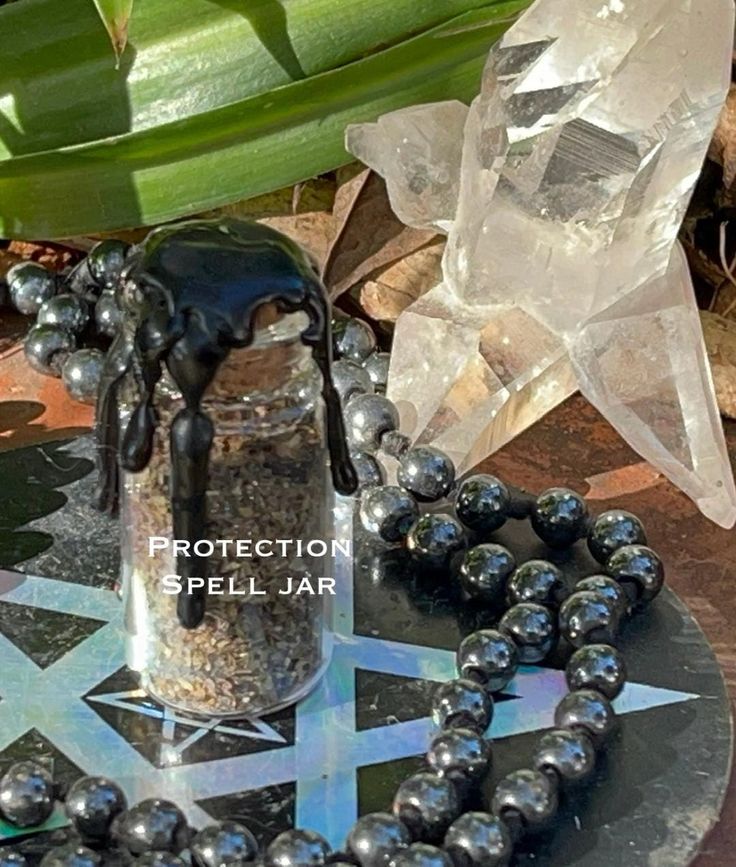 a table topped with black beads and a glass jar filled with liquid on top of it