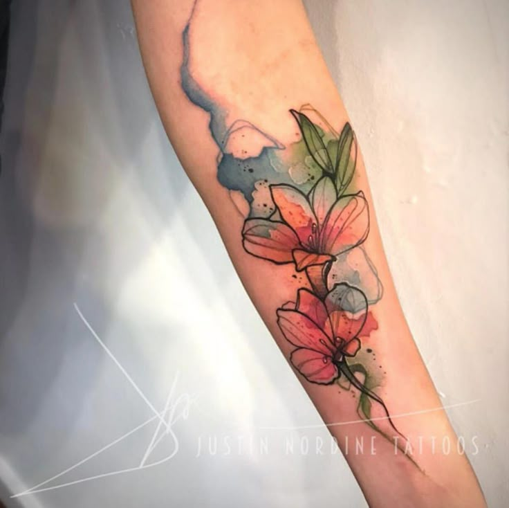 a watercolor style flower tattoo on the arm