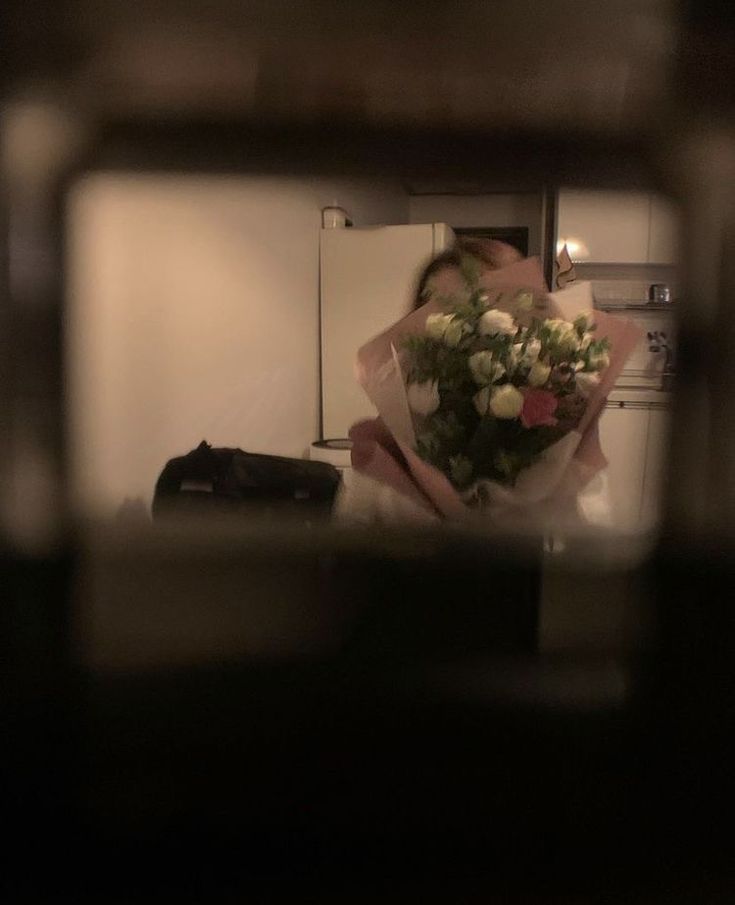 a bouquet of flowers sitting on top of a counter in front of an open refrigerator