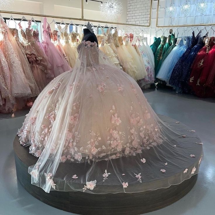 there is a wedding dress on display in the store with many dresses hanging up behind it