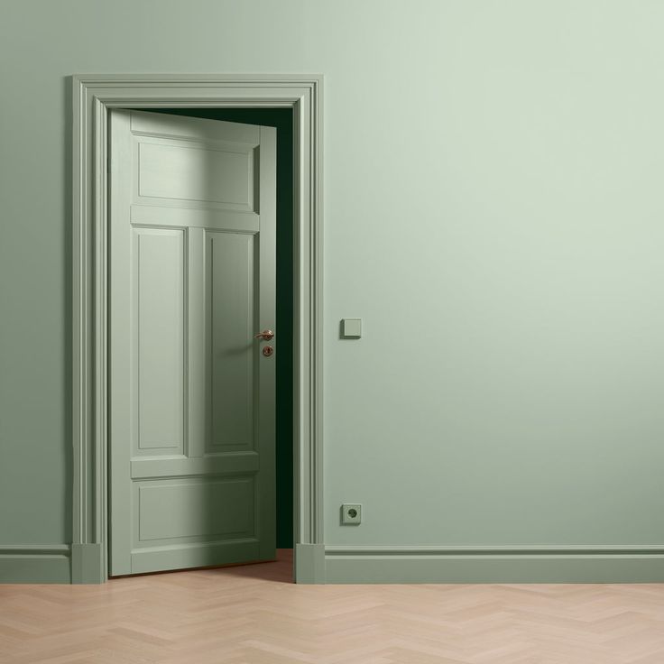 an empty room with a door open to another room and wood floors in front of it