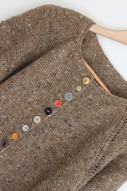 a brown sweater with buttons on it and a wooden stick sticking out of the back