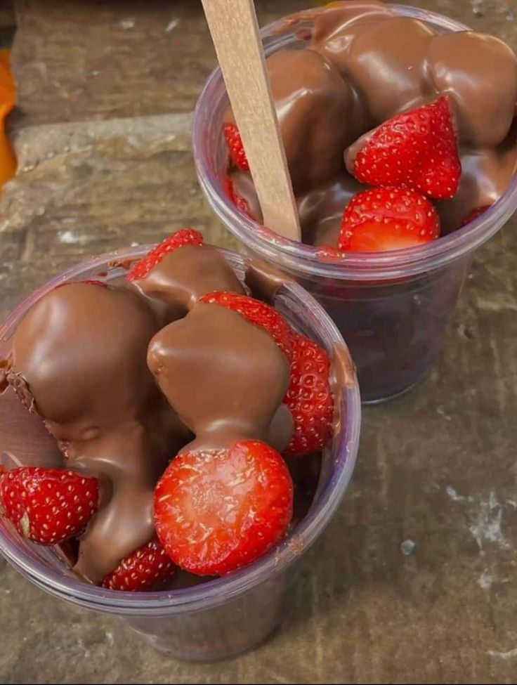 two plastic cups filled with chocolate and strawberries