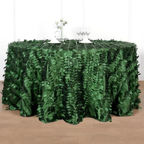 a table covered in green leaves with a vase on top