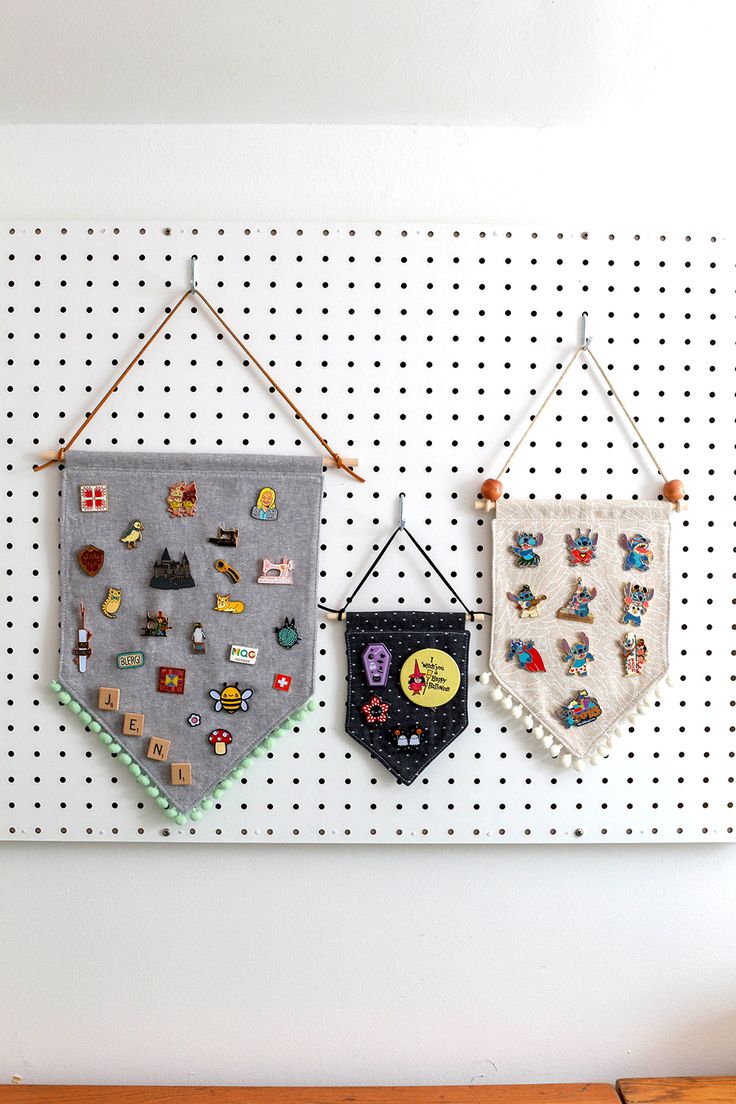 two wall hangings on a peg board with pins and magnets