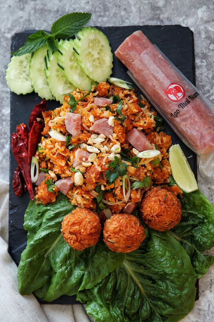 a black plate topped with meatballs and veggies next to cucumbers