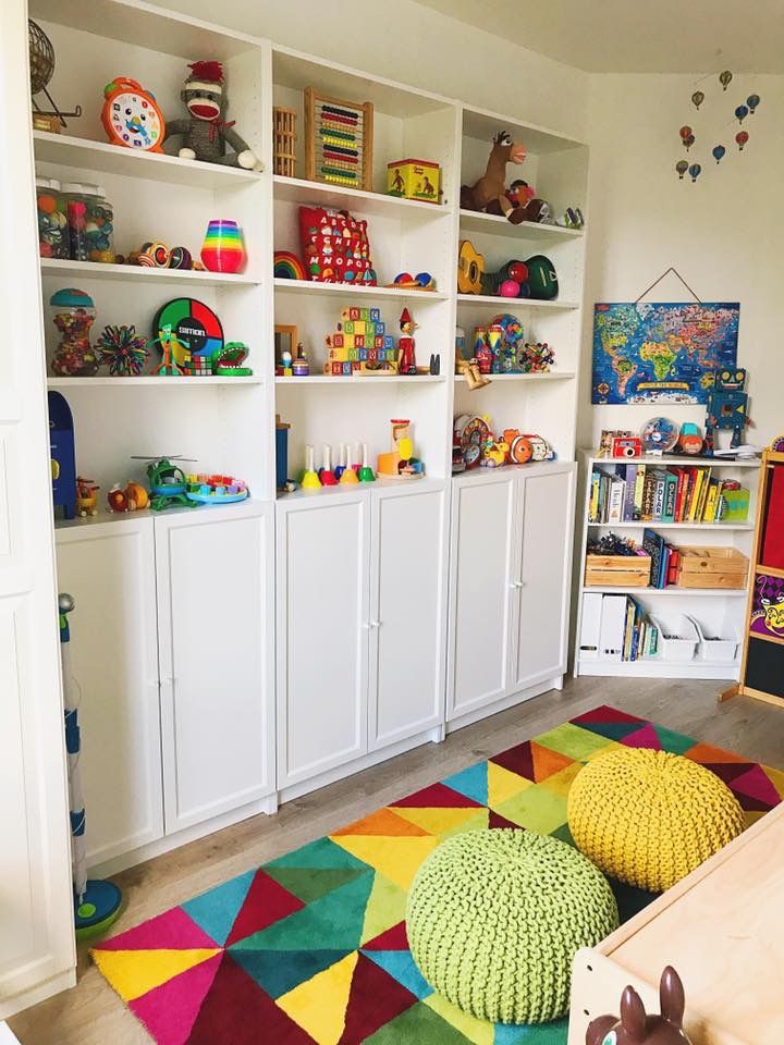 a child's playroom with toys, bookshelves and rugs on the floor