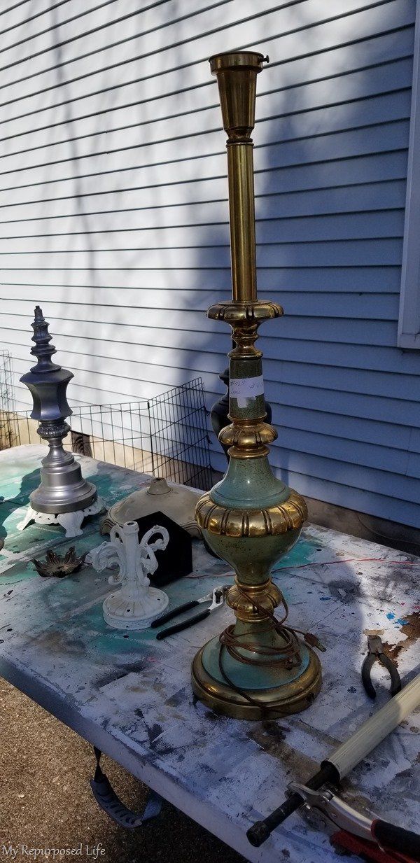 an old lamp is sitting on top of a table with paint all over the surface