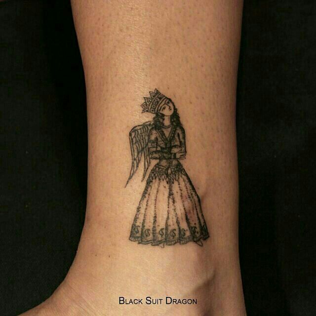 a tattoo on the foot of a woman wearing a dress with an angel wings above her head