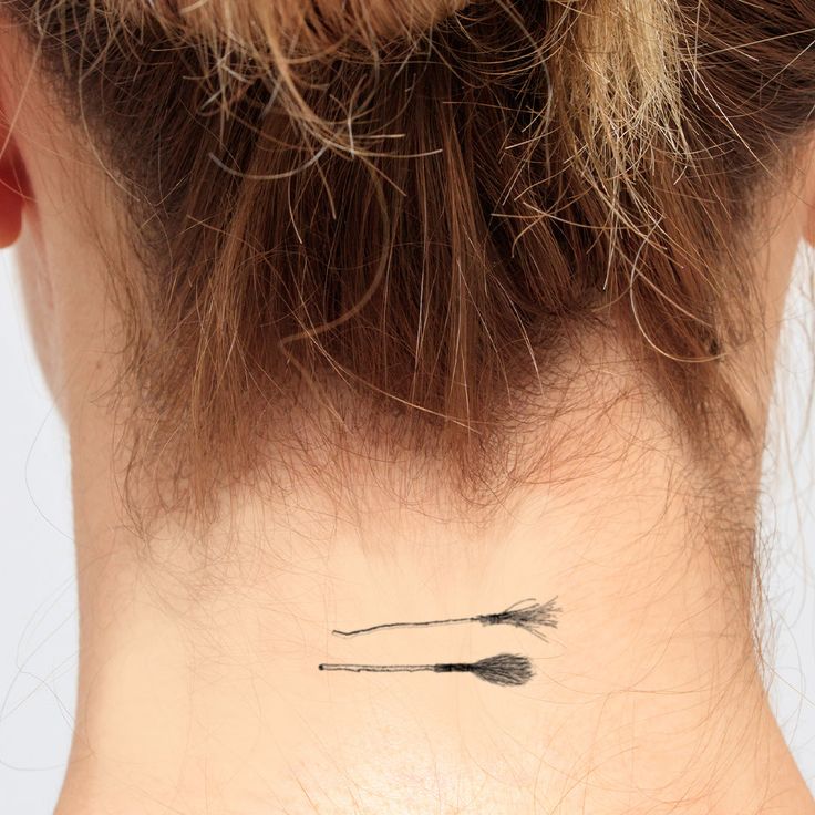 the back of a woman's neck with an arrow tattoo on her left side