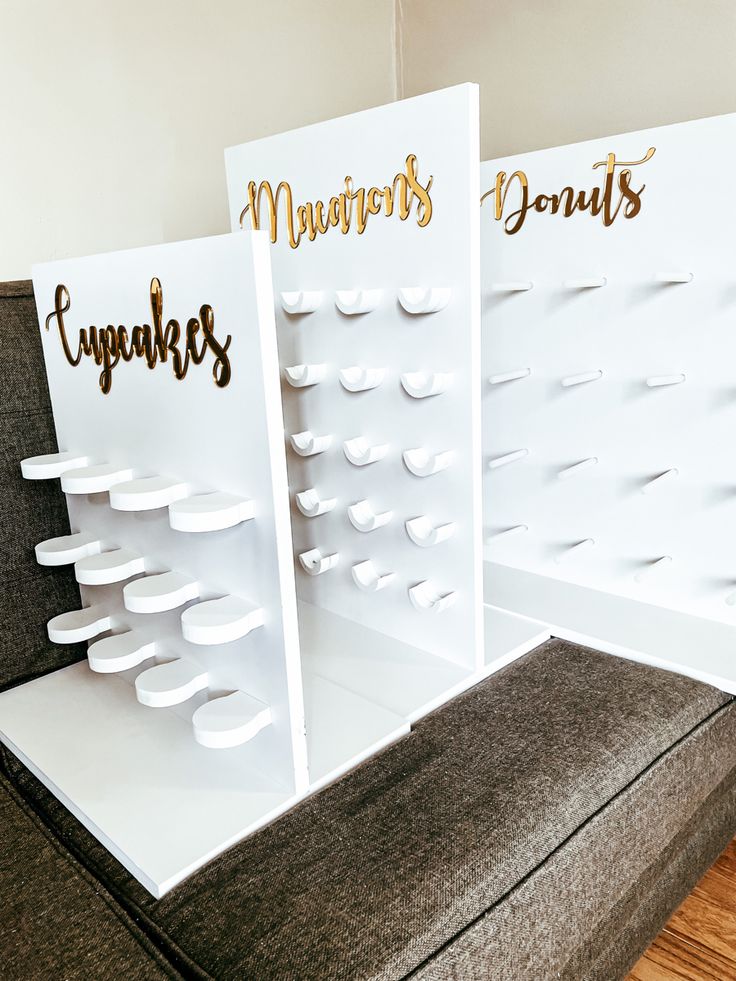 three display boards with gold lettering on them sitting on top of a gray couch in front of a white wall