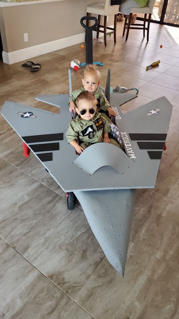 two young boys sitting on top of an airplane