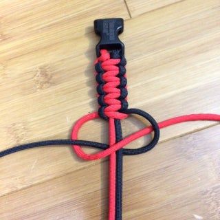 a red and black leash on top of a wooden floor