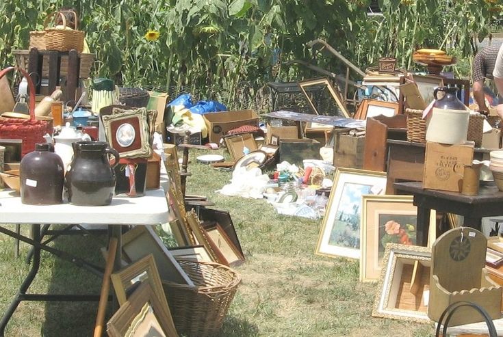 an outdoor flea market with sunflowers and pictures on the ground, including vases