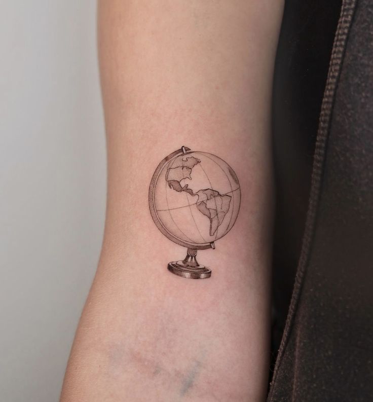 a small globe tattoo on the arm