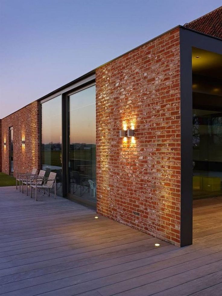 a brick building with two lights on it's side and some chairs in the background