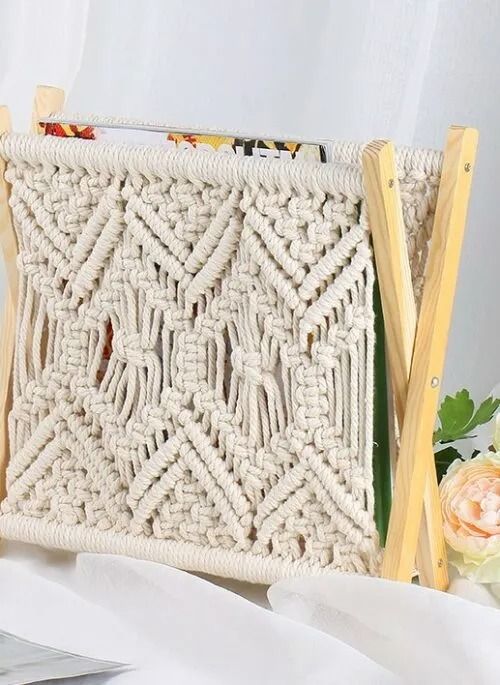 a white crocheted bag sitting on top of a table next to flowers and scissors