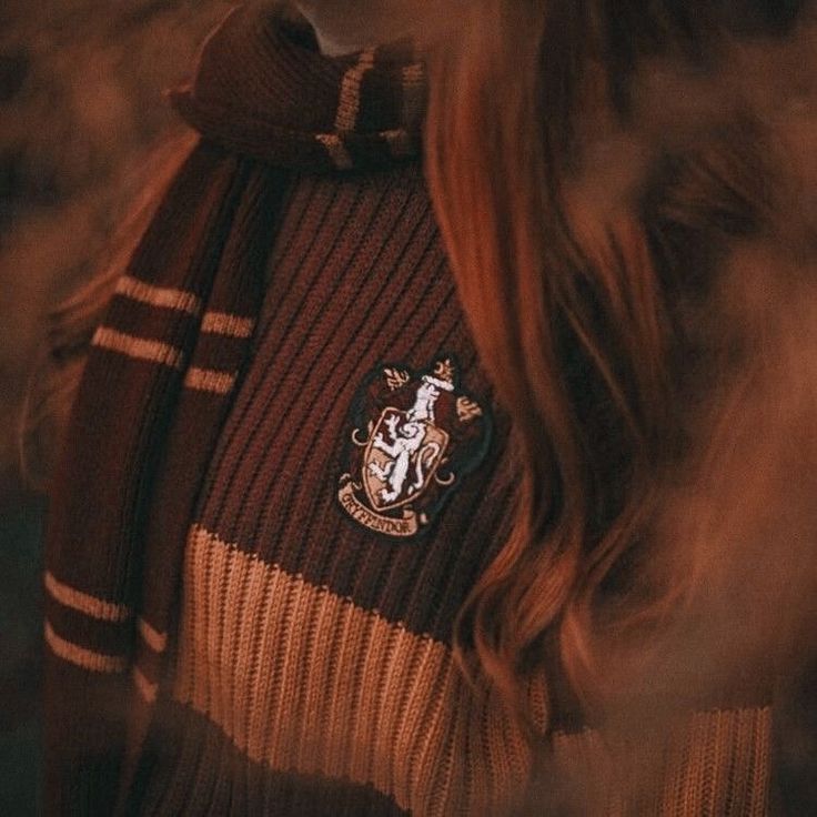 a woman wearing a harry potter sweater with her hair blowing in the wind and looking off into the distance