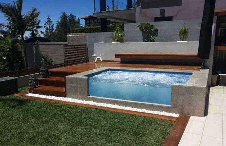 a small swimming pool in the middle of a yard with steps leading up to it