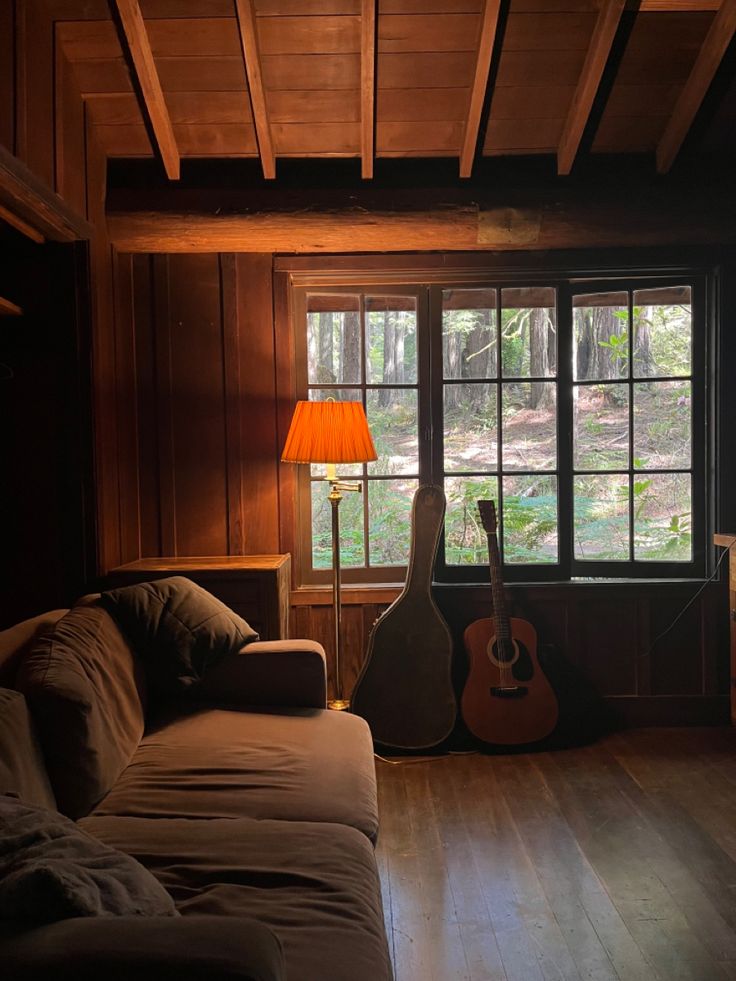 a living room filled with furniture and a guitar sitting on the floor next to a window