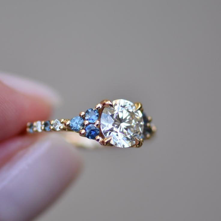 a person holding a diamond and blue sapphire ring