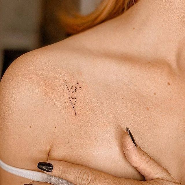 a woman's shoulder with a small tattoo on the left side of her breast