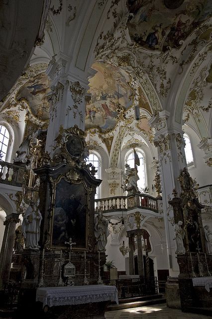 the interior of an old church with ornate paintings on the walls and ceiling, along with pews