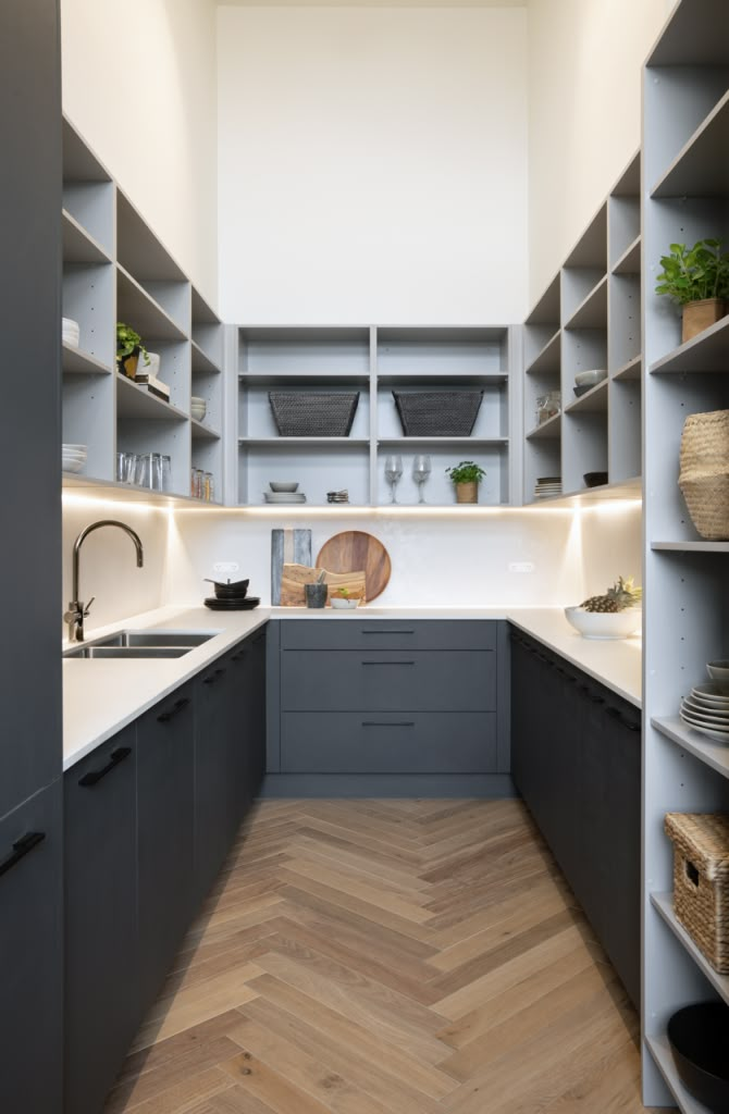 an empty kitchen with wooden floors and gray cupboards on either side of the counter