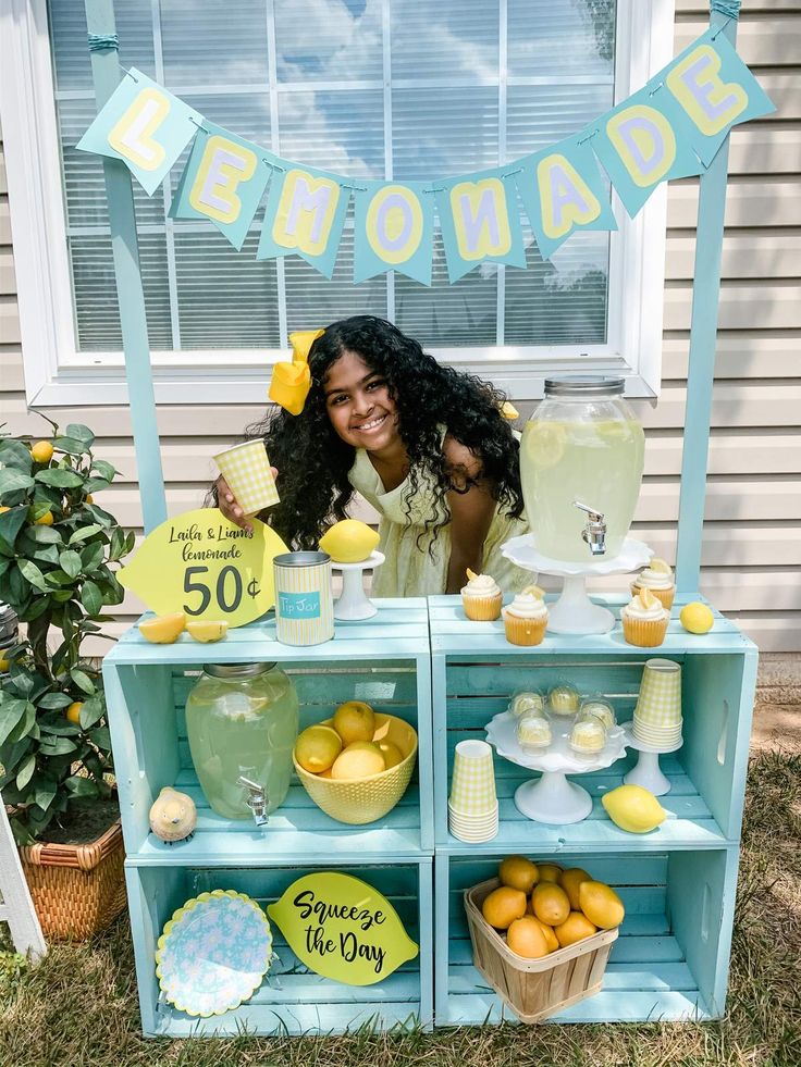 a woman standing in front of a lemonade stand