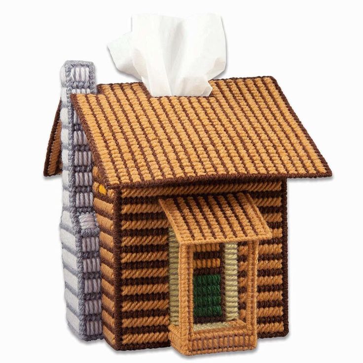 a brown log cabin with a tissue dispenser on the roof and a roll of toilet paper in front of it