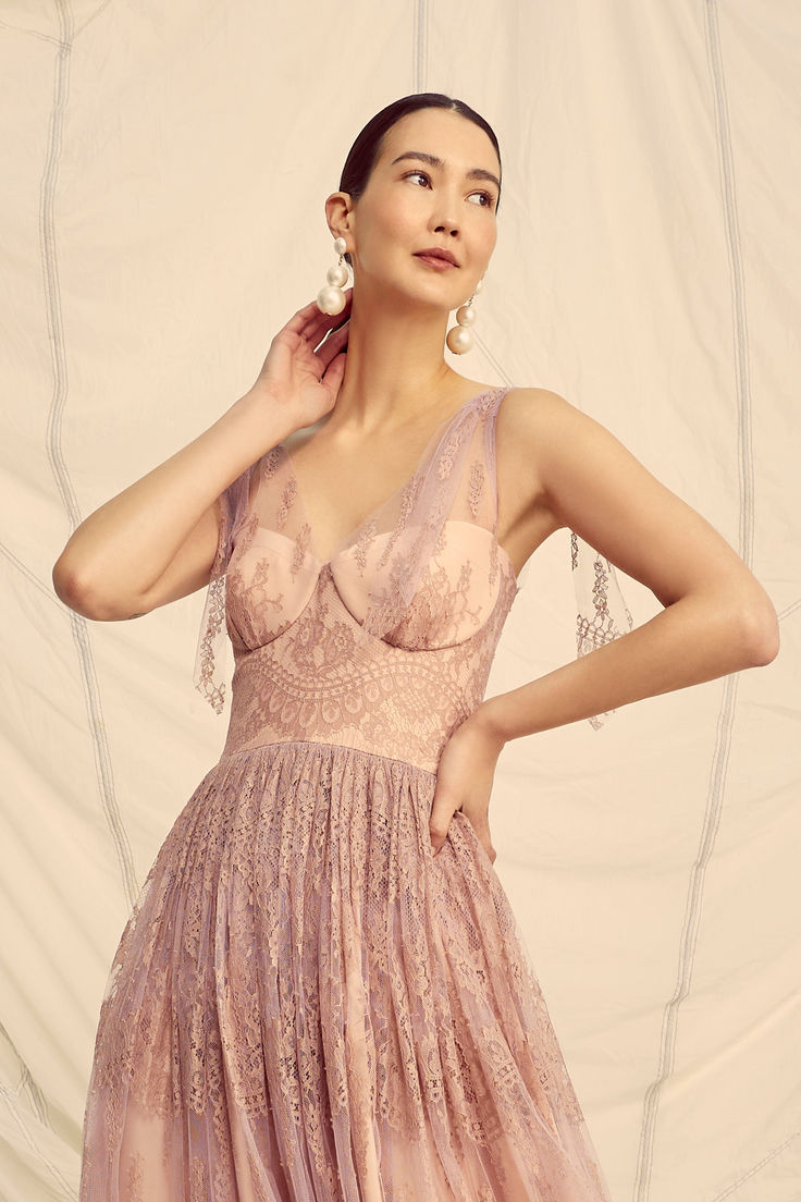 a woman in a pink dress poses for the camera with her hands on her head