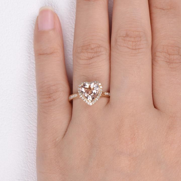 a woman's hand with a heart shaped diamond ring on top of her finger