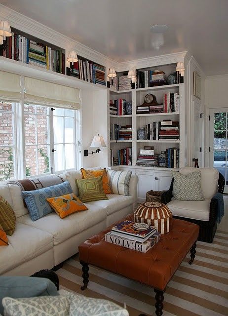 a living room filled with lots of furniture and bookshelves full of books on top of them