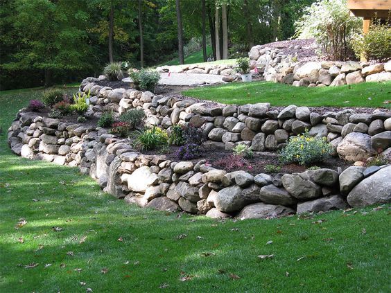 a stone wall in the middle of a grassy area