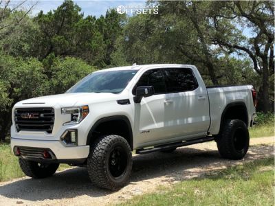 a white truck parked on top of a dirt road next to some grass and trees