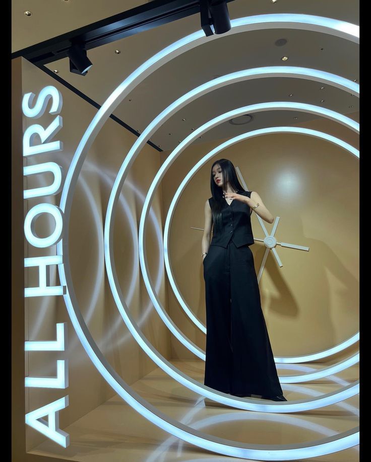 a woman is standing in front of a display with white lights and circular rings on it