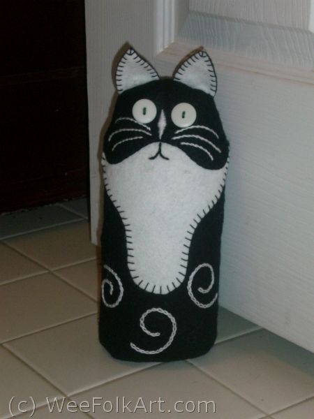 a black and white cat stuffed animal next to a door