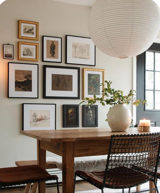 a dining room table with chairs and pictures on the wall in front of it,