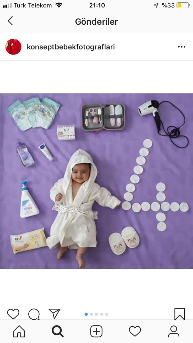 a baby in a bathrobe surrounded by personal care items on a purple blanket