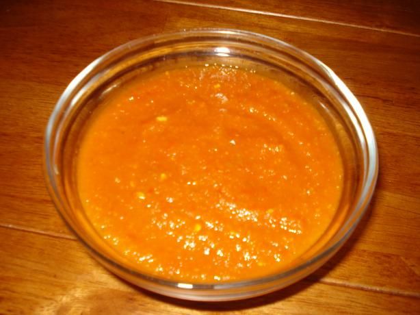 a glass bowl filled with sauce on top of a wooden table