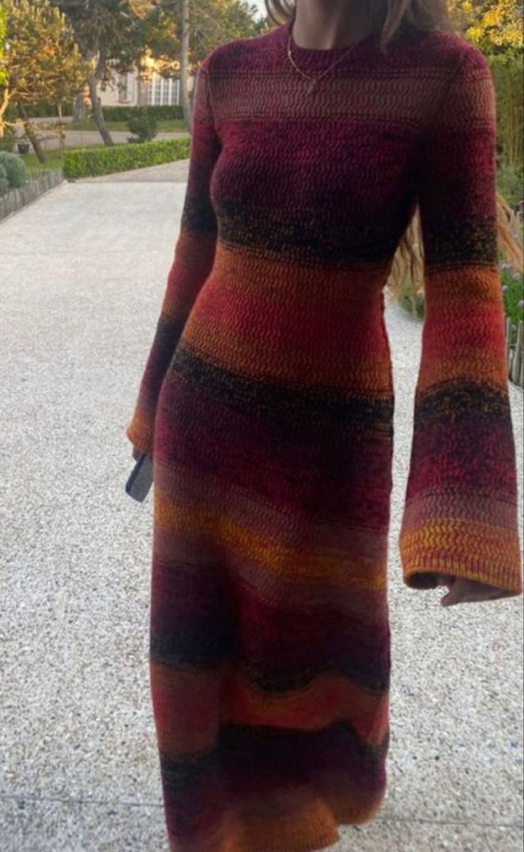 a woman is walking down the street wearing a long knitted dress with bell sleeves