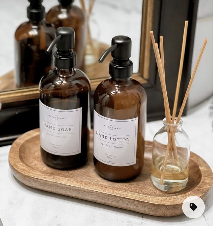 two bottles of hand lotion sit on a wooden tray