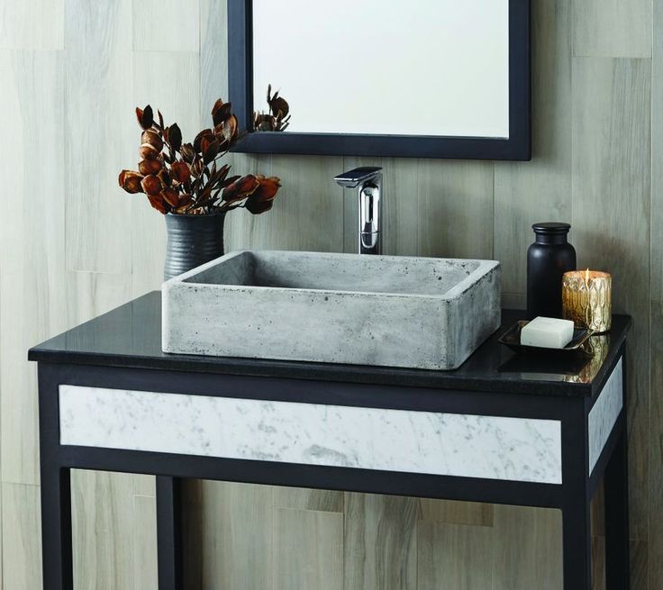 a bathroom sink sitting under a mirror next to a vase