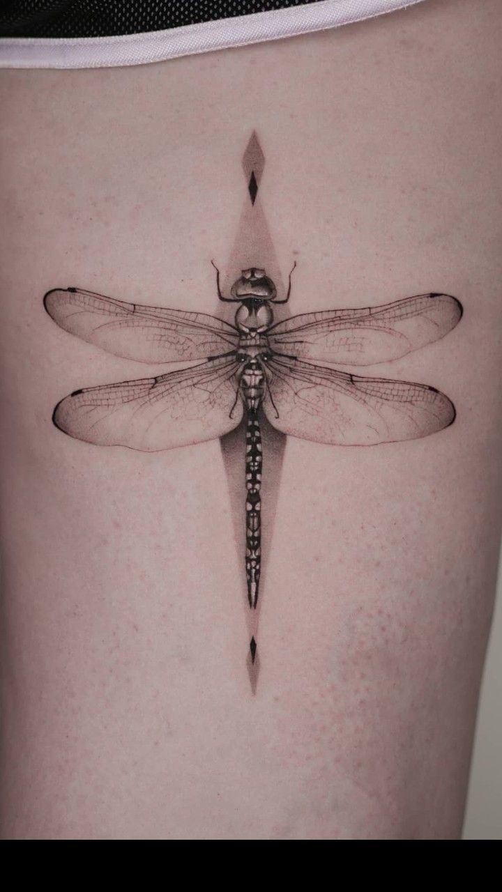 a black and white photo of a woman's stomach with a dragonfly tattoo on it