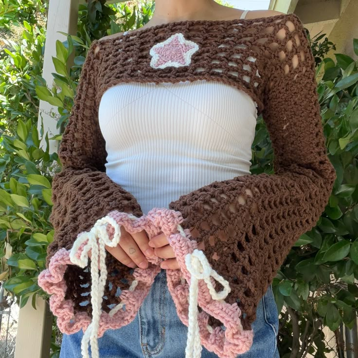 a woman wearing a brown crocheted sweater with pink and white flowers on it