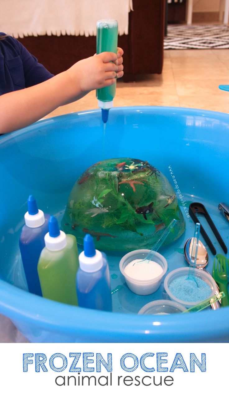 a child is playing in a blue tub filled with water and other items to make an ocean animal rescue